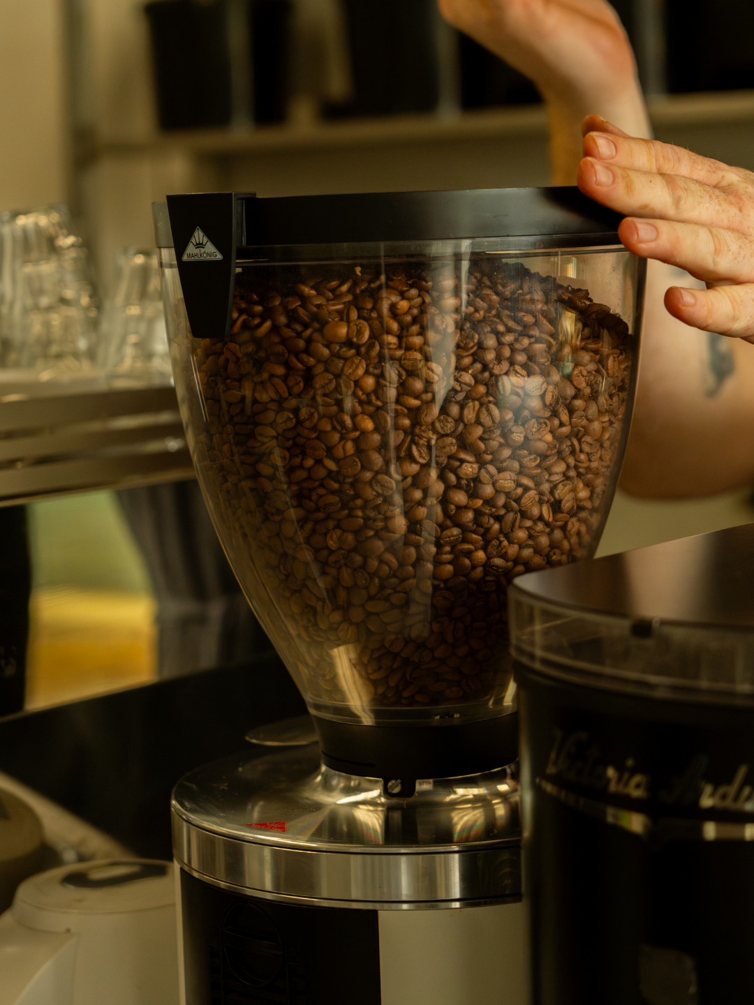 Coffee grinder filled with coffee beans being operated by a hand